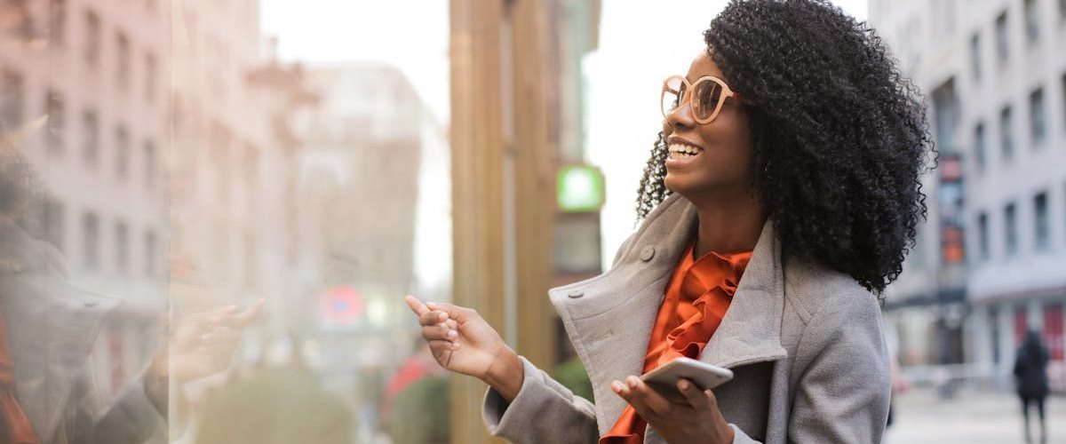 Happy woman with curly hair shopping in the city, reflecting joy and a trendy lifestyle.