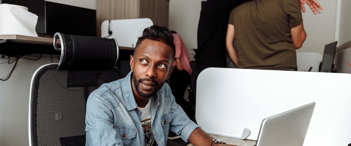 Young man working on a laptop in a modern collaborative office environment.