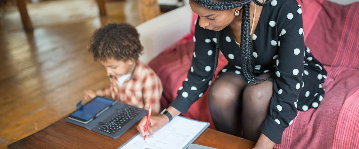 Mother multitasking with work and child at home, showcasing modern parenting.